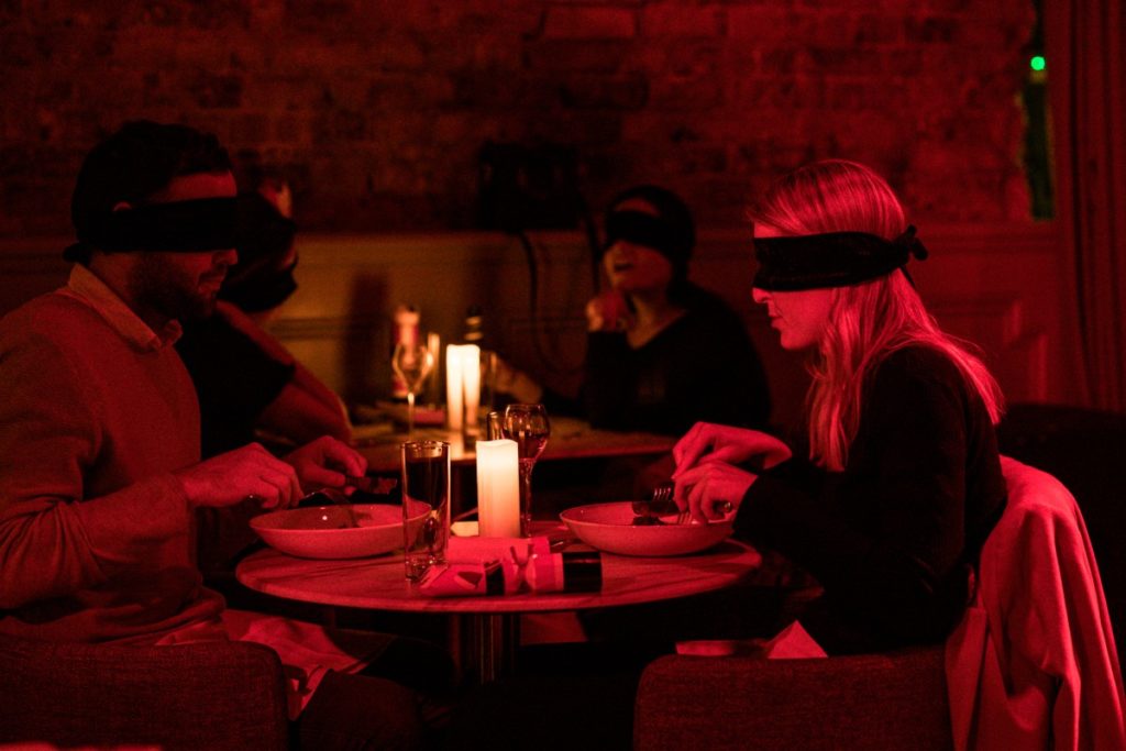 A blindfolded couple having an intimate dinner at Dining in the Dark