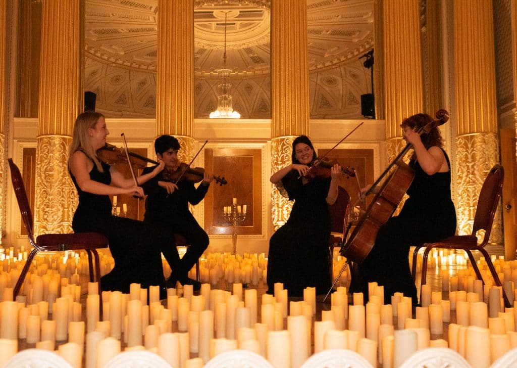 A string quartet play in St. George's Hall, surrounded by candles.