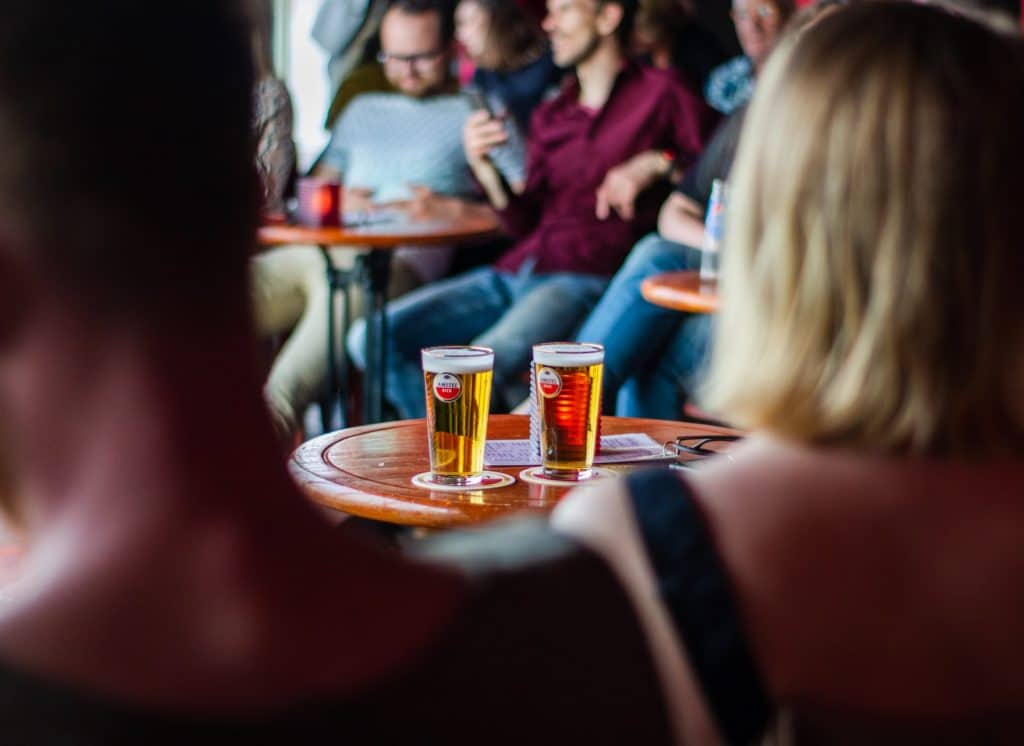 Two pints of beer sit on a pub table as people complete a pub quiz. 
