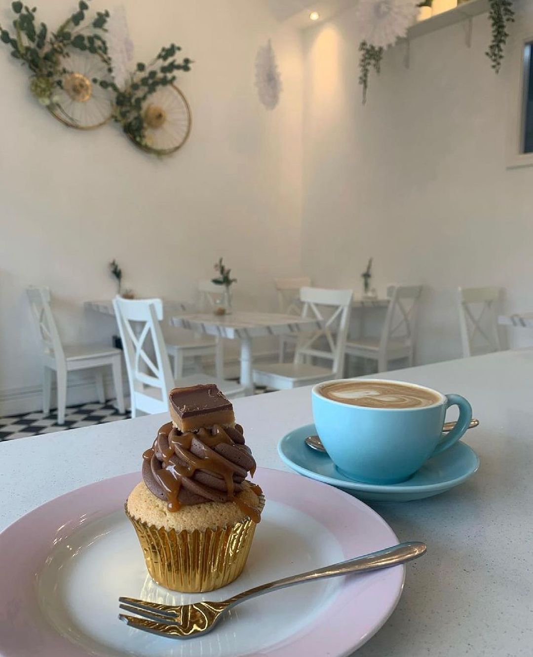 A table, on which sits a chocolate covered cupcake and a cup of coffee at Catherine Braidy Cake Parlour.