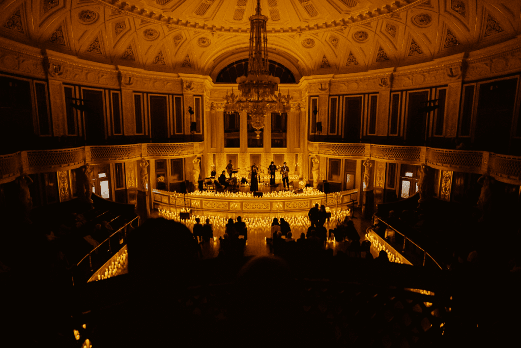 A band performing on a candlelit stage inside St George's Hall in Liverpool and teh audience in darkness.