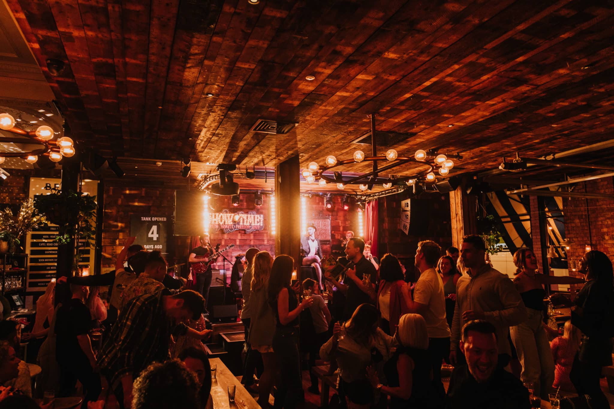 A dimly lit bar at Albert Schloss where a crowd is watching a band play.