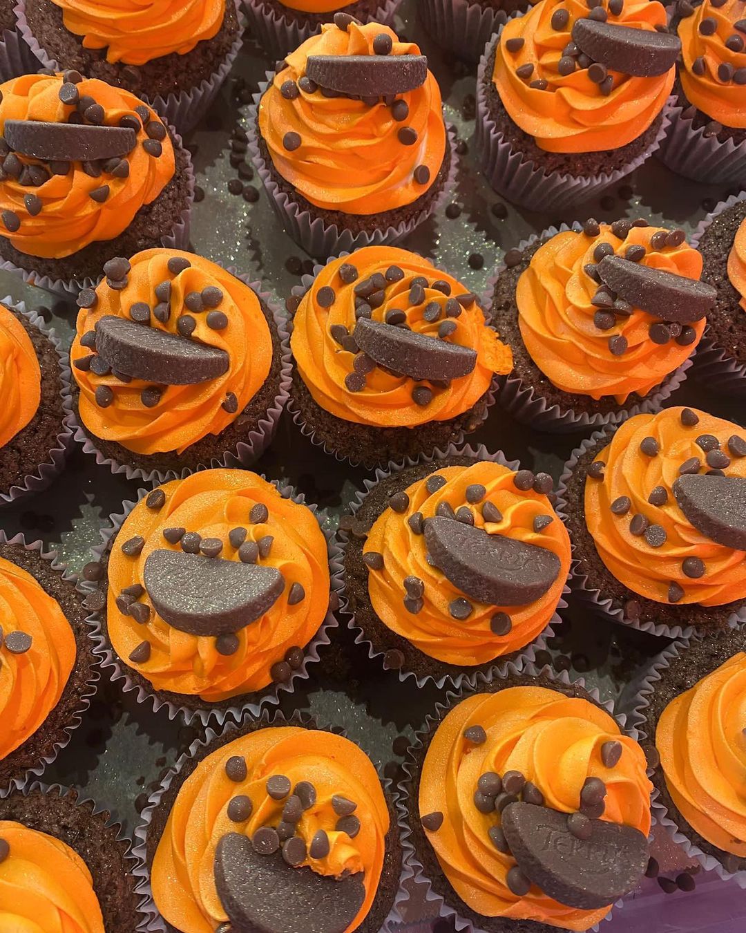 A tray of cupcakes with orange icing and chocolate orange segments at Finch Bakery.