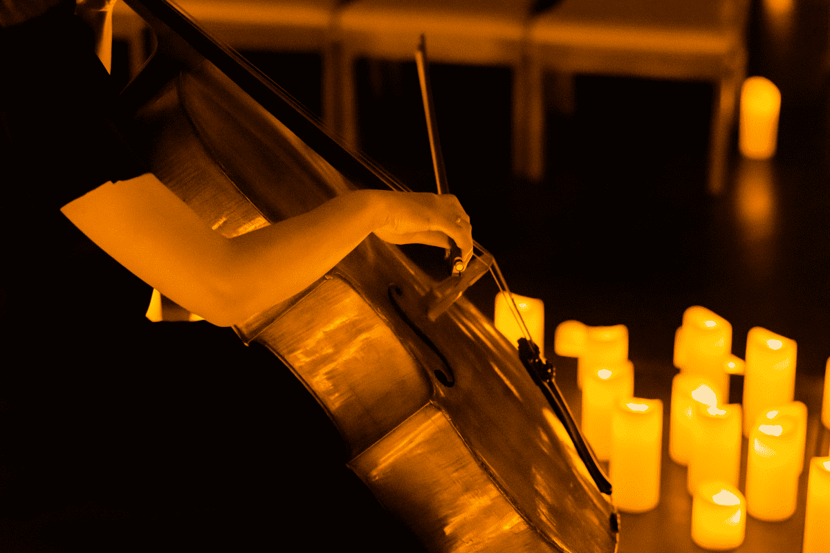 A cello playing performing while surrounded by candles