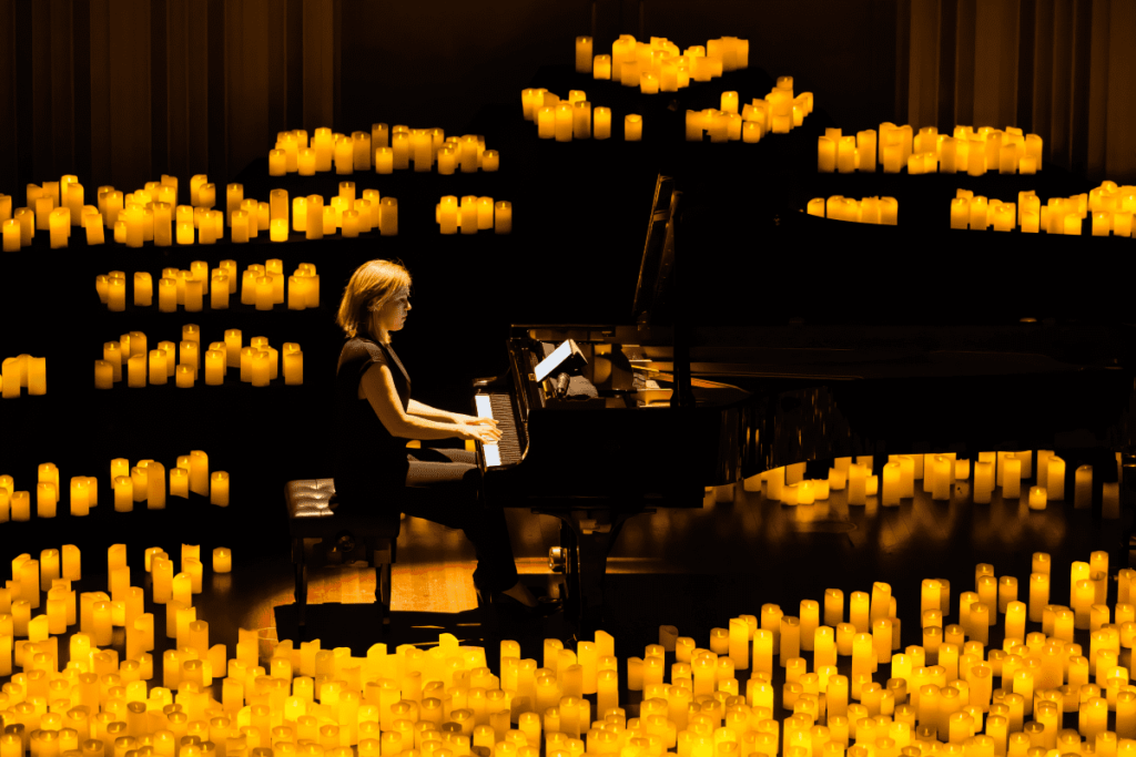 A woman playing the piano surrounded by hundreds of candles.