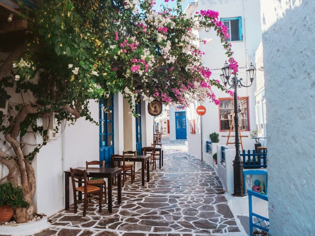 The exterior of a Greek restaurant with a tiled floor and tables.