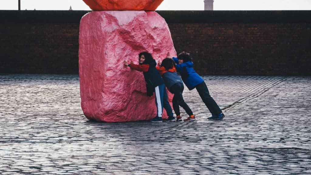 Three children hug the sculpture outside of Tate Liverpool.