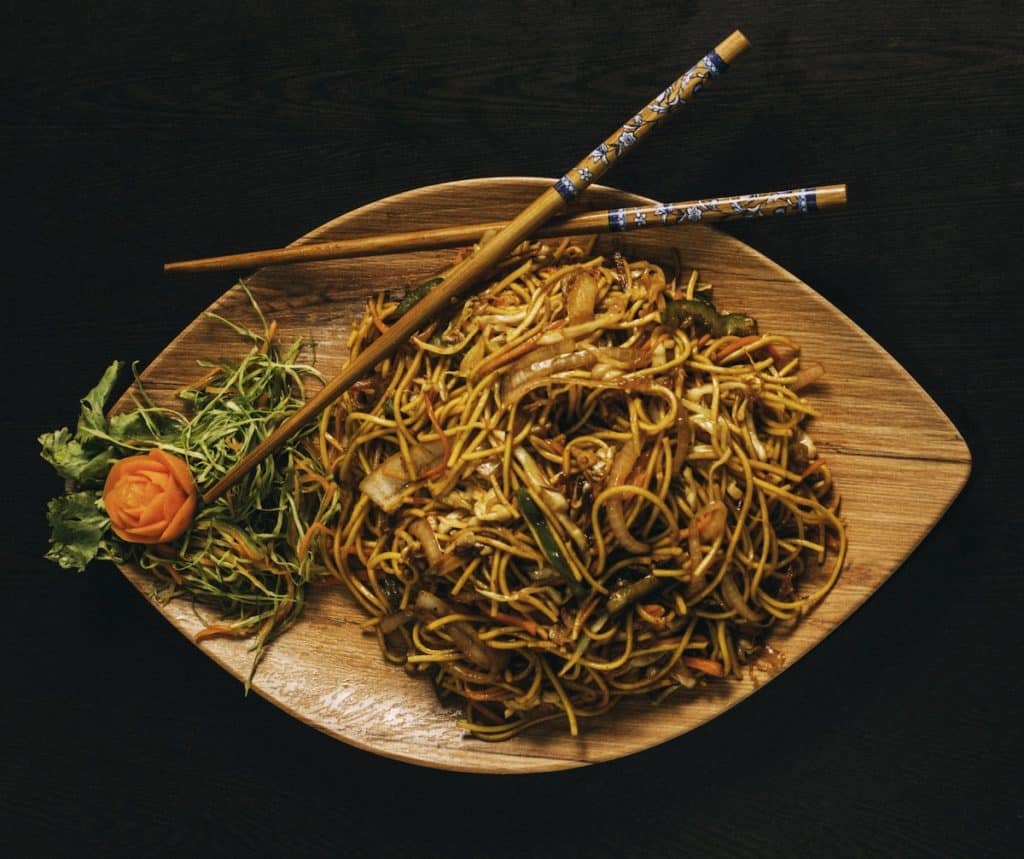 A plate of noodles with chopsticks.